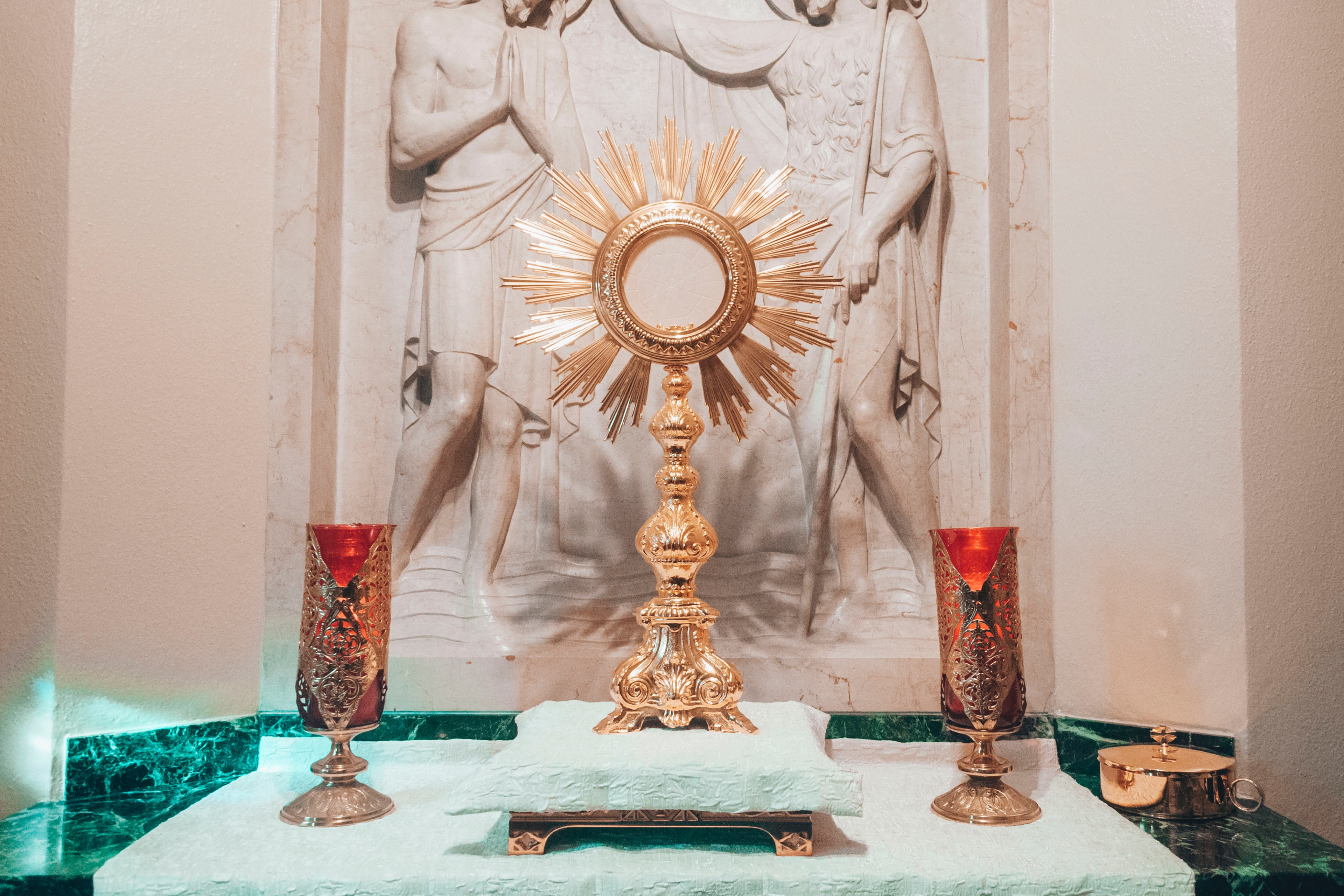 A photo of the Blessed Sacrament exposed in a monstrance, with lit candles either side.